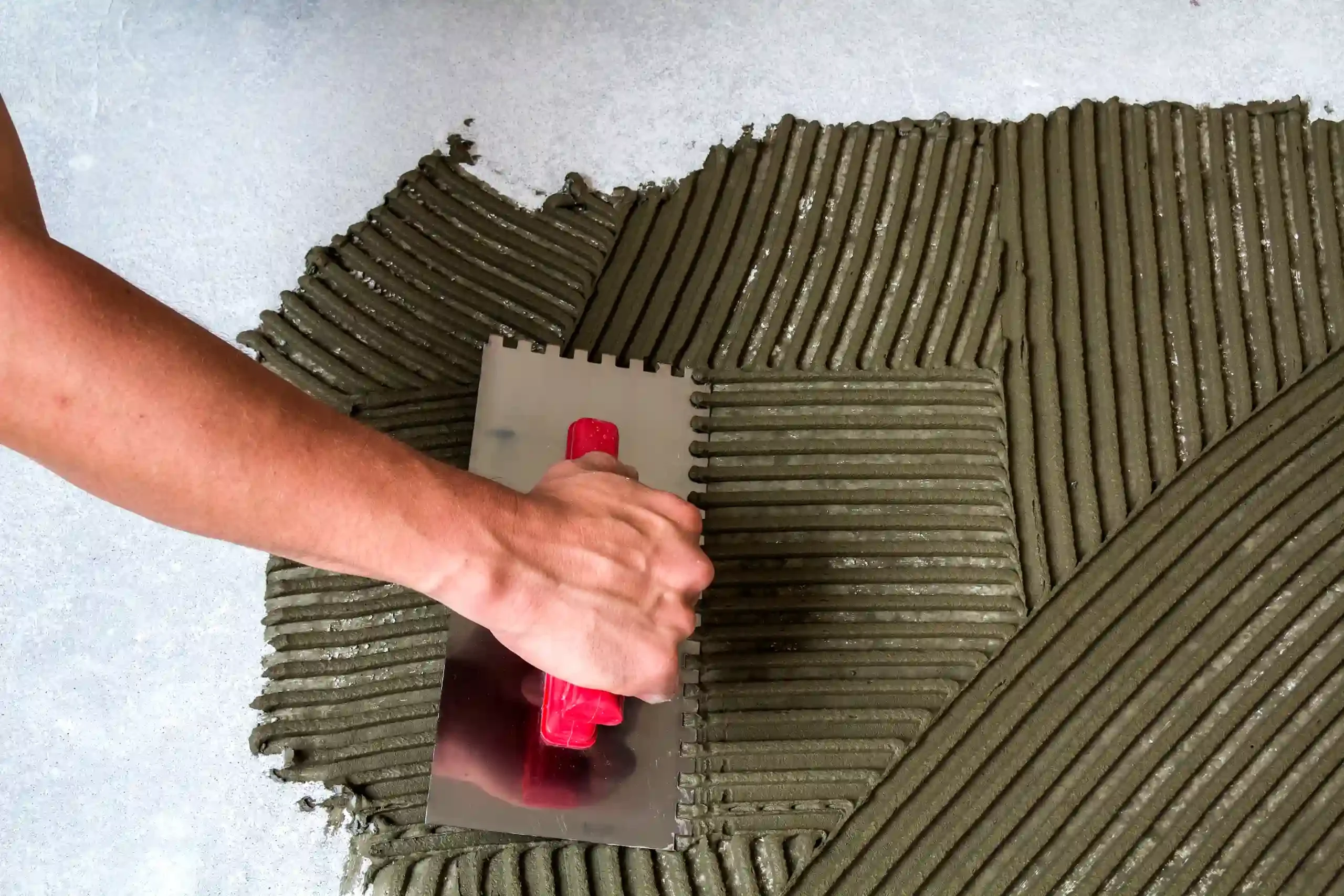 worker-hand-with-trowel-tool-for-tiles-installatio-2024-12-06-01-37-53-utc